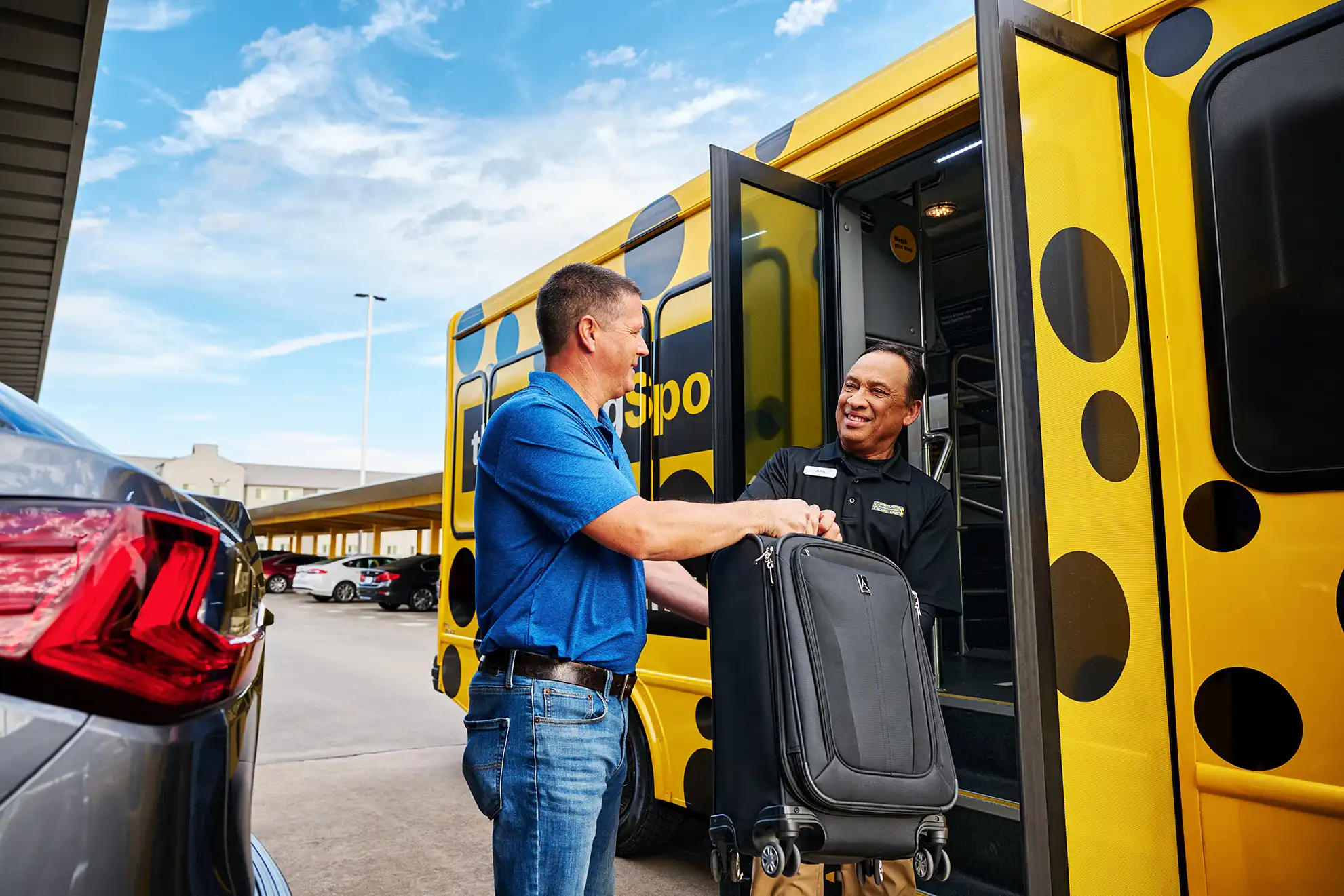 Airport shuttle driver helps a guest of The Parking Spot with his bags.