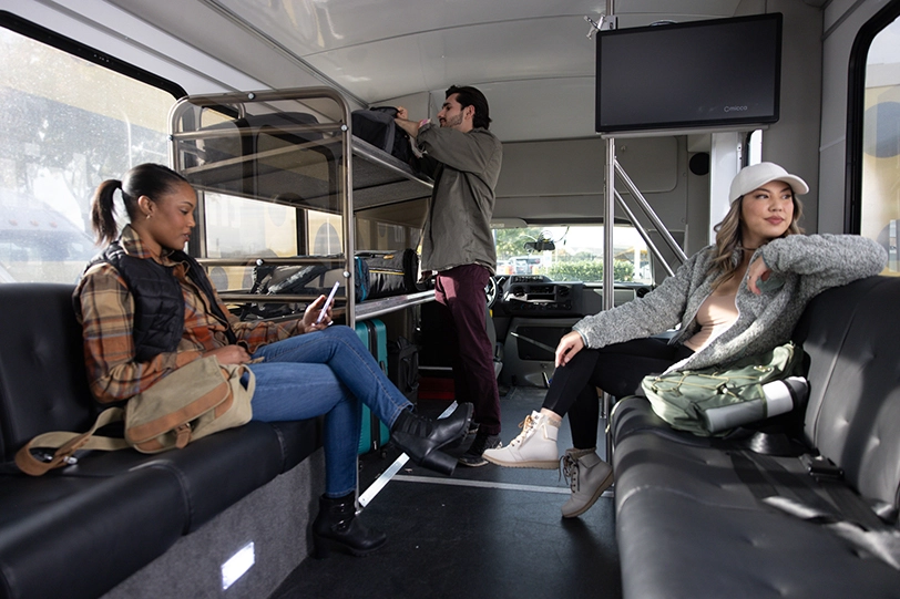 A family of three inside an Airport Shuttle checks in on a mobile device.