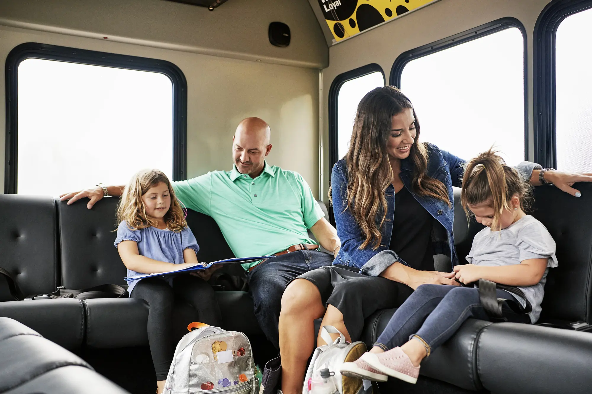 Parents with two girls settle in to their airport shuttle ride.